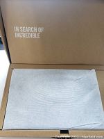 Unopened ASUS laptop in cardboard packaging with protective sleeve and “In Search of Incredible” slogan
