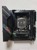 Top view of the ASUS ROG Strix motherboard showing CPU socket, RAM slots, and heatsinks with ROG branding.