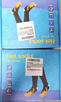 Photo of two boxes of heated socks with packaging showing socks with flames on toes indicating heating, labeled 'Hot Socks For Winter'.