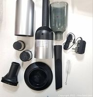 All components of the handheld vacuum cleaner laid out on a white surface showing various accessories and charger.