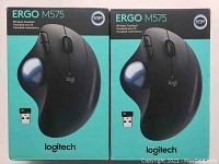 Photo showing two Logitech ERGO M575 Wireless Trackball boxes side by side from the front with teal backgrounds and product image.