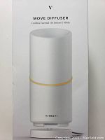Photo of the front of the box shows the Vitruvi Move Cordless Essential Oil Diffuser in white color with a gold accent ring and the charging base beneath it.