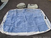 Both deflated mattresses spread out with accompanying storage bags shown on a paved surface.