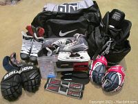 Youth hockey equipment including Bauer VaporX LTX skates, CCM skates, gloves, blade guards, and Nike bag