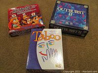 Three boxed games: Hedbanz, Outburst II, and Taboo placed on carpeted floor