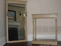 Bleached oak hall table and mirror standing side by side in a room showing the full structure and brass hooks on mirror