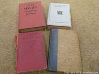 Top-down view of four vintage hardcover books on beige carpet, shows colors, wear, and condition of covers.
