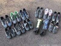 Overview of all black and colored soccer cleats arranged on ground with shin guards in center