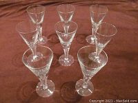 Photo of 7 stemmed crystal glasses arranged in a triangular formation showing clear textured stems and bowls.