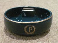 Front view of vintage Palmer House Hotel ashtray showing 'P' emblem with gold laurel wreath on dark green glazed ceramic.