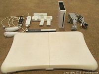 All components of the lot laid out on a carpeted floor including balance board, Wii console and accessories.