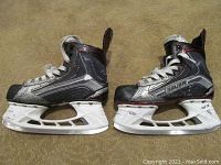 Side view of both black and grey Bauer VaporX LTX youth hockey skates showing wear and TUUK blade holders.