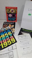 Overview photo showing five music books and sheets including 'The History of Rock Music' and guitar instructional materials.