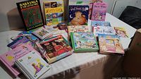 Photo showing various children's books spread out on a table including Baba Yaga & The Little Girls, Let's Go!, and a Disney Princess Collection book.