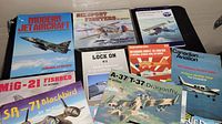 Books and magazines on a table showing aircraft titles such as Modern Jet Aircraft, MiG-21 Fishbed, SR-71 Blackbird, A-37 T-37 Dragonfly, and The Red Arrows.