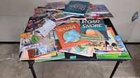 Photo showing a large pile of boys' books spread on a table, includes colorful illustrated children's books such as 'Daddy', 'Roar and Snore', and others, all in read condition.