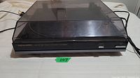 Front view of the Black Realistic turntable with dust cover closed, showing brand name and control buttons.