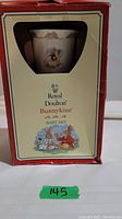 Photo of the original box in red with Royal Doulton Bunnykins Baby Set branding and illustration of bunnies on the front.