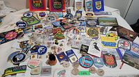 Photo showing an assortment of vintage patches, pins, and postcards laid out on a white surface.