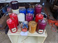 Lot of 12 unused scented pillar candles displayed on a tray, assorted colors and some with labels.