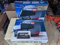 Two boxed Chatter Box Sports Communication System units on a table, with branding visible on boxes and units.