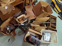 Overview of multiple cardboard boxes containing curved and straight pieces of model railroad track, small buildings, and other hobby accessories.