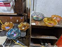 Overview photo showing five carnival glass bowls in different iridescent colors and shapes arranged on a surface.