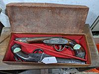 View of the two pistol-shaped decanters in original lined box, showing overall set condition and arrangement.