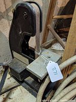 Photo showing the black benchtop narrow belt sander with metal base and visible sanding belt. Unit has dust and cobwebs indicating long storage.