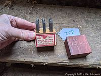 Hand holding steel numeric stamps and wooden case with label showing Millers Falls model 1550 and 1/16 inch figures.