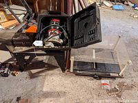 Craftsman router inside black case next to router table on floor in workshop environment