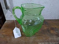 Side view of green Depression glass triangular pitcher showing texture and handle.