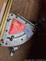 Close-up of the Incra miter gauge showing metal body with angle markings and adjustment knobs.