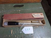 Photo of the complete drill inside the original box with a tag marked 225.