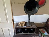 Front view of the antique radio and large metal horn speaker shown on a wooden surface near a door.