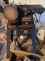 Front and side view of Sears Craftsman belt and disc sander mounted on metal stand with visible dust and wear.