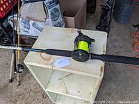 Full view of Shakespeare Sturdy Stik fishing rod with reel attached. Shows black foam handle grips, and reel with bright yellow line.