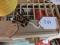 Two vintage rusted metal railroad keys attached to a string with tags reading 'Golden Goose Line' and 'Central Maine Key'. Keys placed on a beige surface.