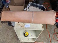 Rolled vegetable tanned leather hide placed on a small white table with measuring tape beneath it to indicate scale.