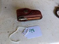 Brown leather textured holster for Swiss Army knife, showing snap button closure and wear from use.