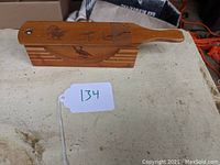Top view of wooden turkey call with engraved turkey images on top and slide mechanism.