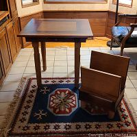 Table, magazine rack, and rug in a corner setting on tile floor