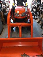 Front view of tractor mounted with LA203A loader and bucket