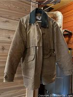 Front view of tan Filson waxed cotton jacket hanging on hanger