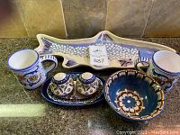 Photo showing entire lot including fish platter, two Starbucks cups, salt and pepper shakers on tray, and pottery bowl on kitchen counter.