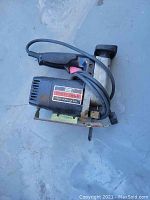 Single image showing Craftsman auto scroll saw with metal base and black handle, power cord wrapped around handle.