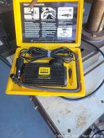 Opened yellow carrying case containing an Intercompressor black ribbed air compressor unit with power cable coiled inside and a nozzle adapter; instruction manual printed on case lid.