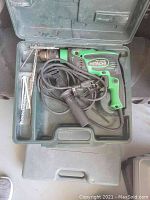 Photo showing Hitachi electric drill model FDV 16vB2 inside molded plastic carrying case with side handle, power cord, drill key, and two drill bits.
