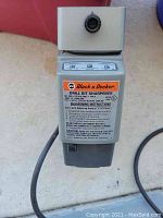 Front view of the Black & Decker drill bit sharpener showing label with sharpening instructions and adjustment knob on top.
