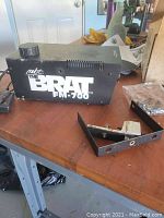 Black MBT The Brat FM-700 fog machine with mounting bracket on tabletop